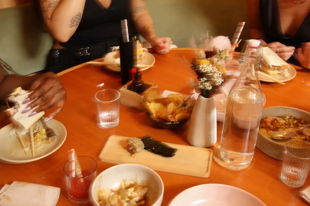 an overhead of shared plates, chips, and cocktails mid-meal